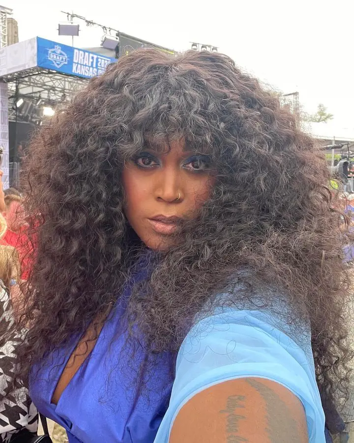 Selfie of Brenda taken during the 2023 NFL Draft as she flaunts her curly hair in a blue dress